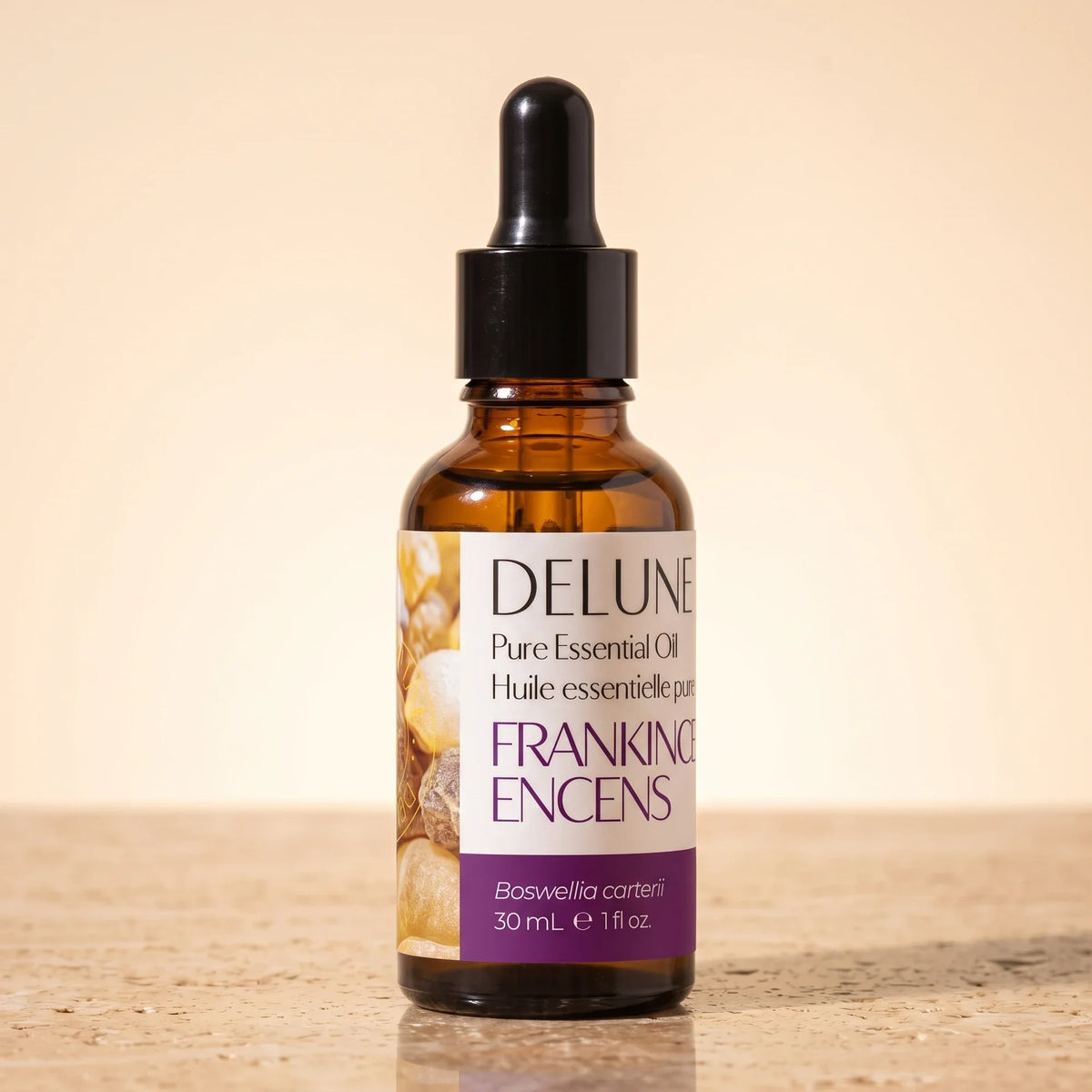 Delune Frankincense Pure Essential Oil, 30ml amber glass dropper bottle on warm travertine stone